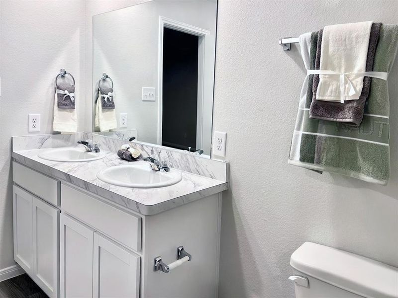 Bathroom featuring double vanity, toilet, and a sink