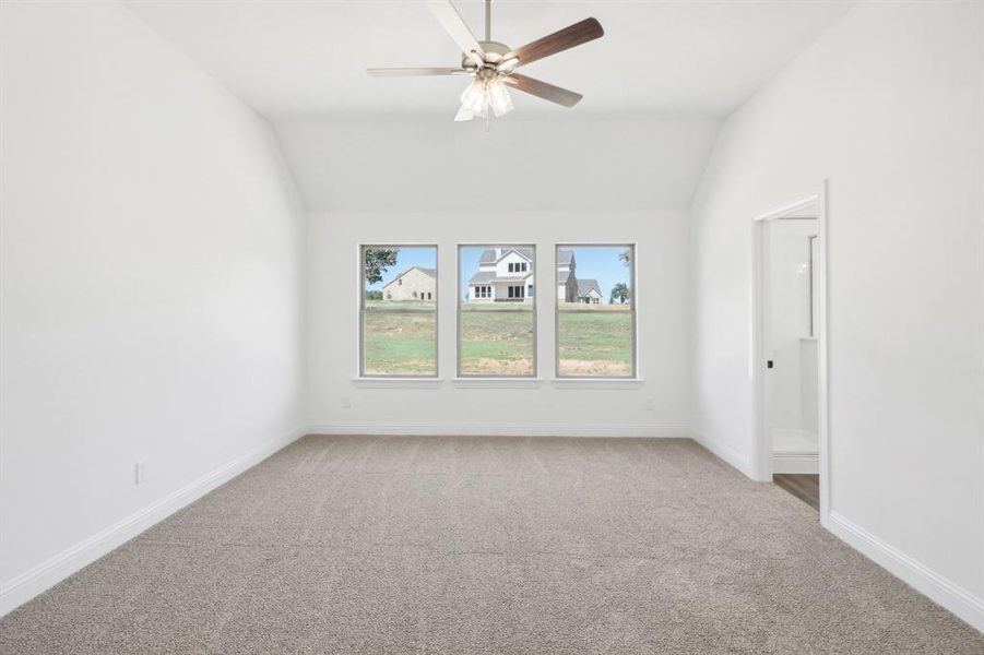 Carpeted spare room featuring ceiling fan and lofted ceiling