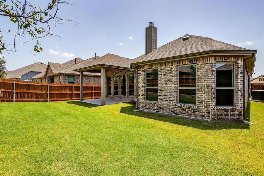 Rear view of house with a lawn and a patio