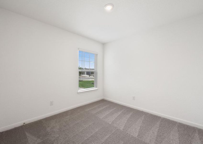 Secondary bedroom with tan carpet and a window.