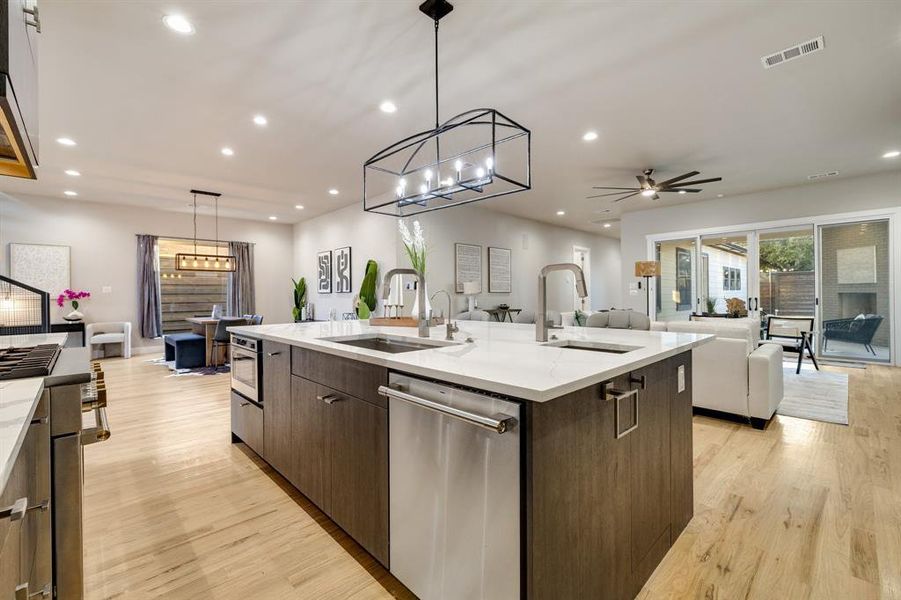 Kitchen featuring appliances with stainless steel finishes, hanging light fixtures, a kitchen island with sink, and sink