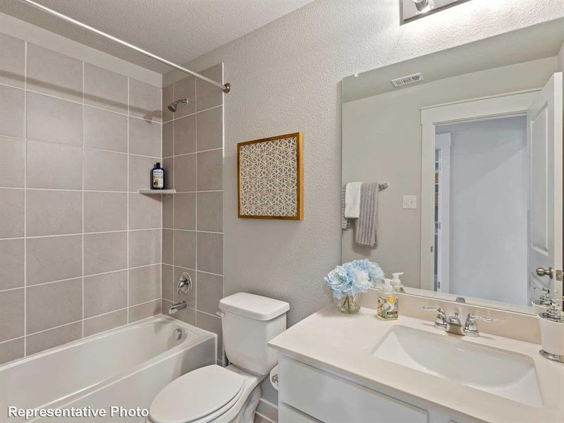 Full bathroom with tiled shower / bath, vanity, toilet, and a textured ceiling