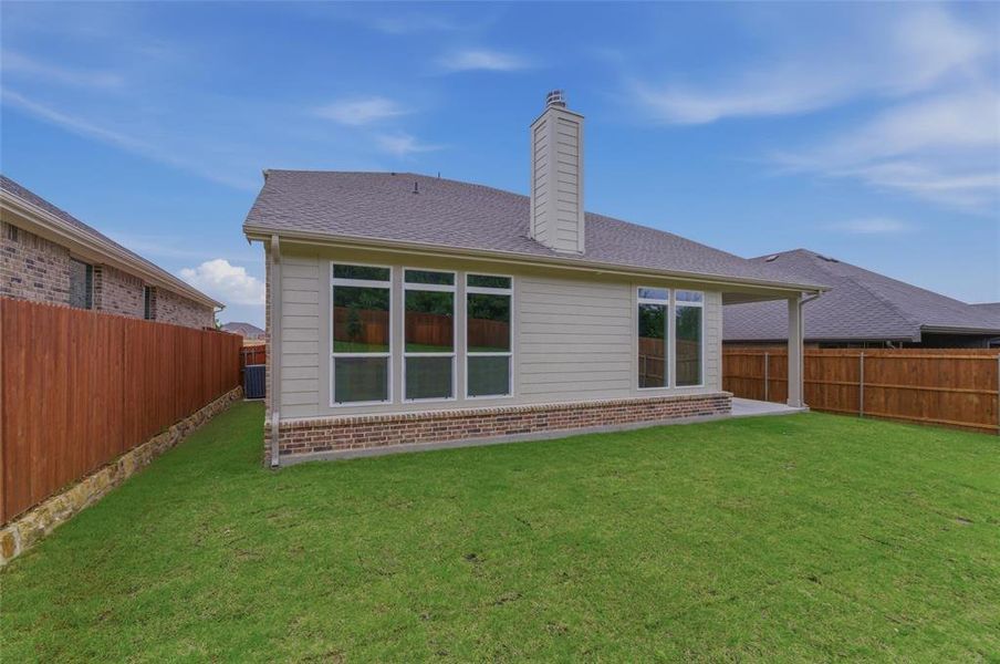 Expansive backyard featuring a manicured lawn, full privacy fencing, and a covered patio
