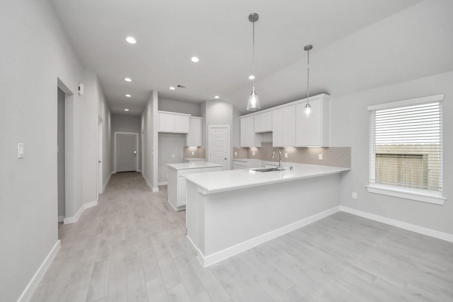 The kitchen is a culinary haven, featuring granite countertops, a tile backsplash, stainless steel appliances, 42” upper cabinets, and undercabinet lighting. Sample photo of completed home with similar floor plan. Actual colors and selections may vary.