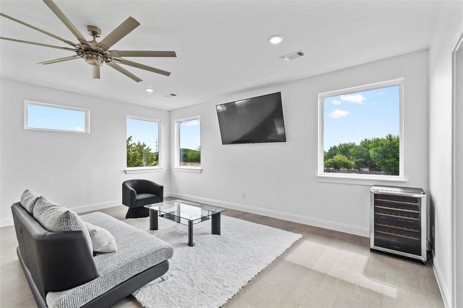 Sitting room with ceiling fan, beverage cooler, and light hardwood / wood-style floors