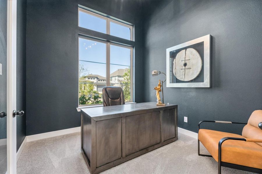 This photo showcases a modern home office with dark walls, a large window for natural light, a sleek wooden desk, and contemporary decor. Perfect for a productive work-from-home environment.