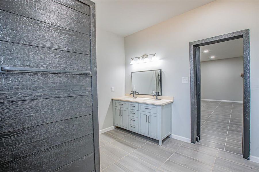 Full bathroom featuring double vanity, baseboards, and a sink