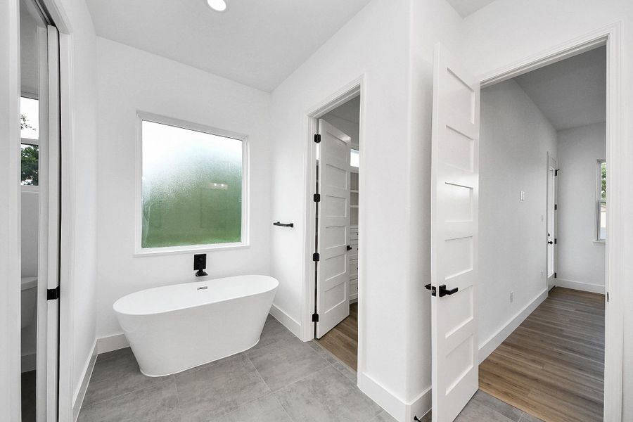 Spa-inspired primary bathroom featuring a sleek freestanding soaking tub, perfect for relaxing and unwinding. Bright, airy design with clean lines creates a serene retreat feel, complemented by modern finishes and a seamless layout.