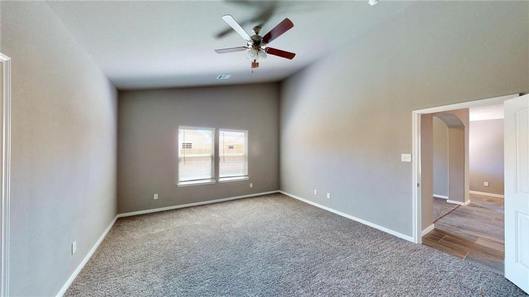 With its neutral tones and spacious layout, the primary bedroom provides a peaceful escape. The ceiling fan adds a touch of modern convenience, while the large windows offer serene views and plenty of natural light. This is a picture of an Elise Floor Plan with another Saratoga Homes.