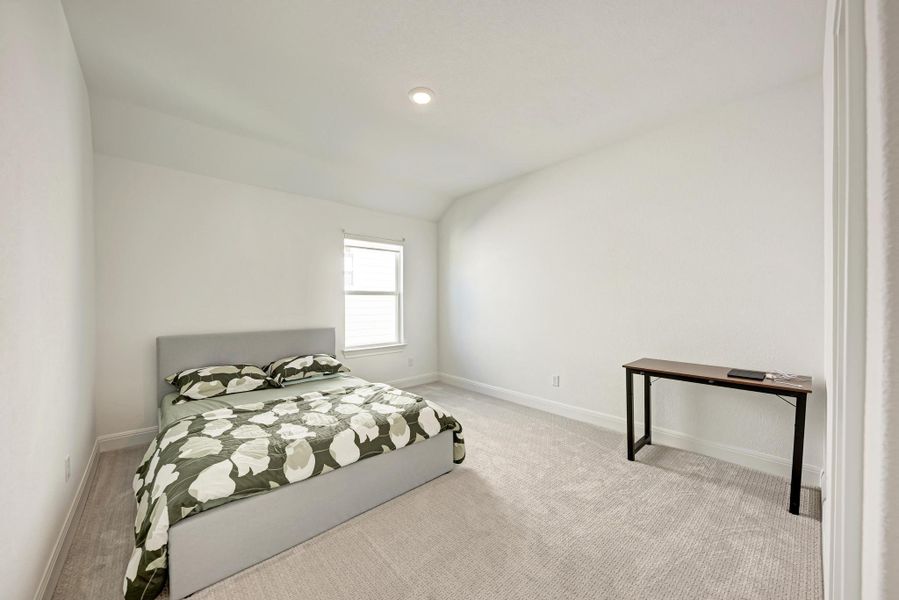 Carpeted bedroom with vaulted ceiling and baseboards