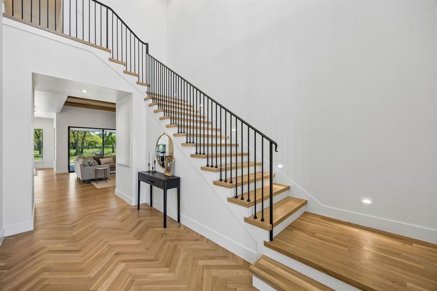 Iron stair rail and a lighted staircase complement the light and airy entrance with a view of the greenbelt.