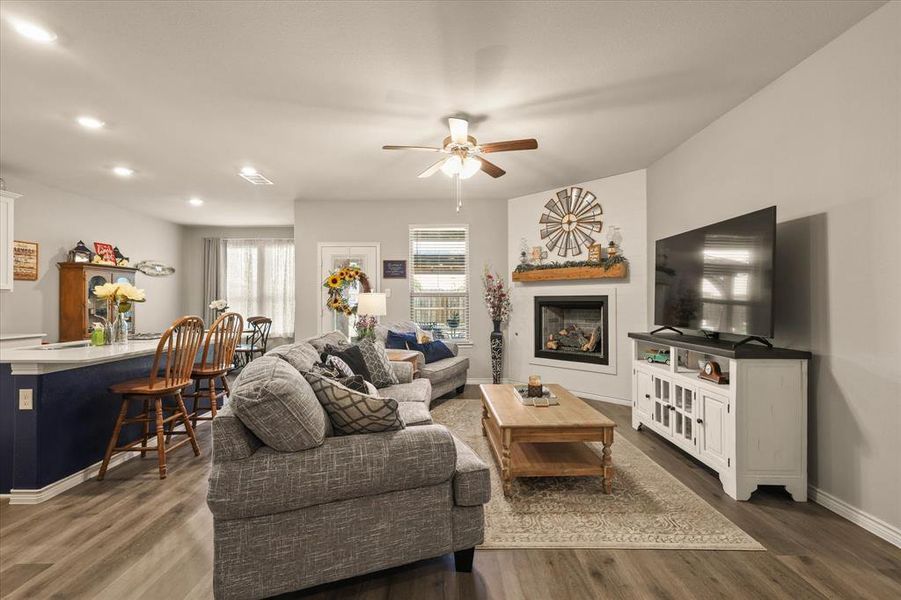 Living room with plenty of natural light, a fireplace, ceiling fan, dark wood-type flooring, and recessed lighting Living room with plenty of natural light, a fireplace, ceiling fan, dark wood-type flooring, and recessed lighting