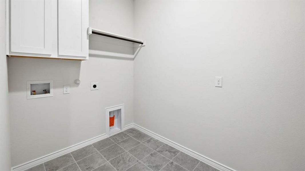 Laundry area with cabinet space, hookup for a washing machine, hookup for a gas dryer, electric dryer hookup, and tile patterned flooring