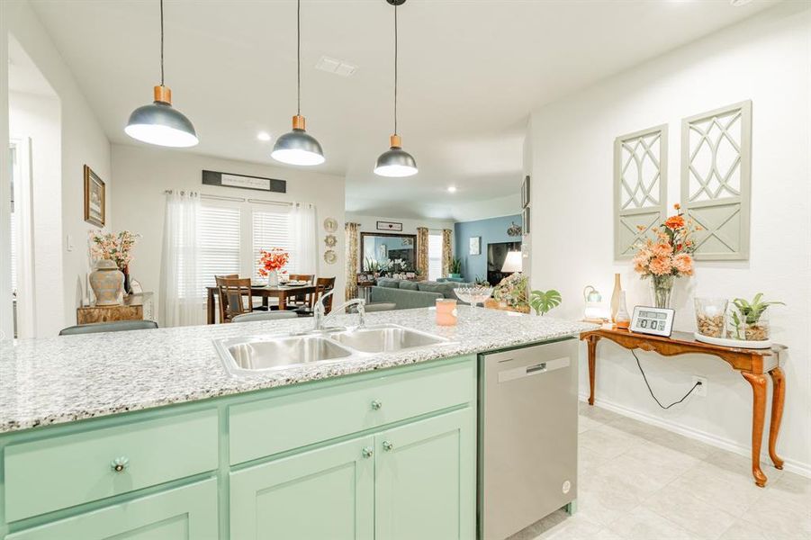 Kitchen with decorative light fixtures, open floor plan, dishwasher, and a sink