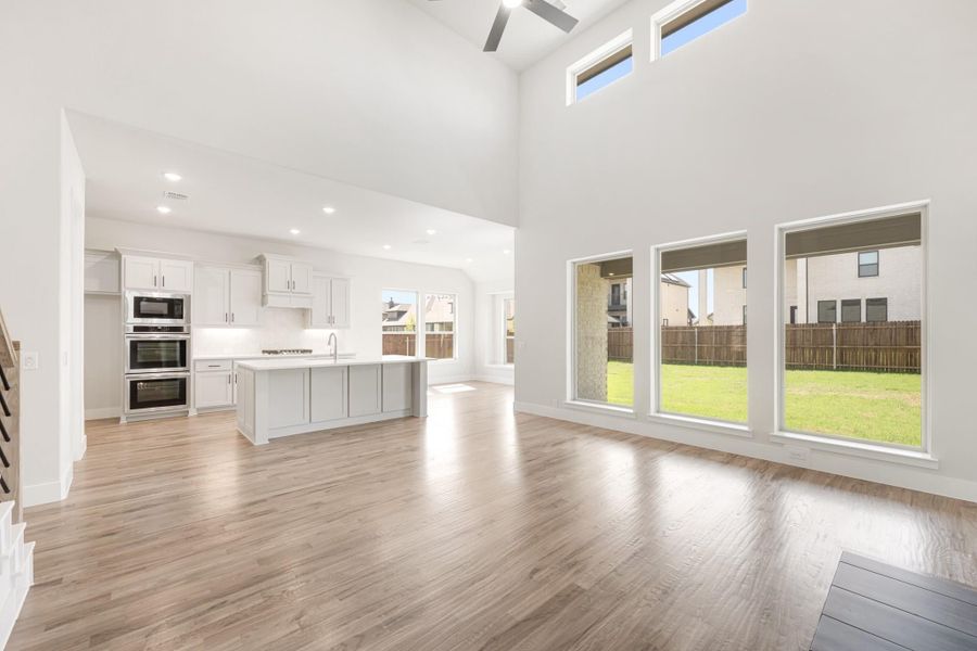 Open living area with hardwood floors and high ceilings flowing into kitchen with gray cabinets and center island