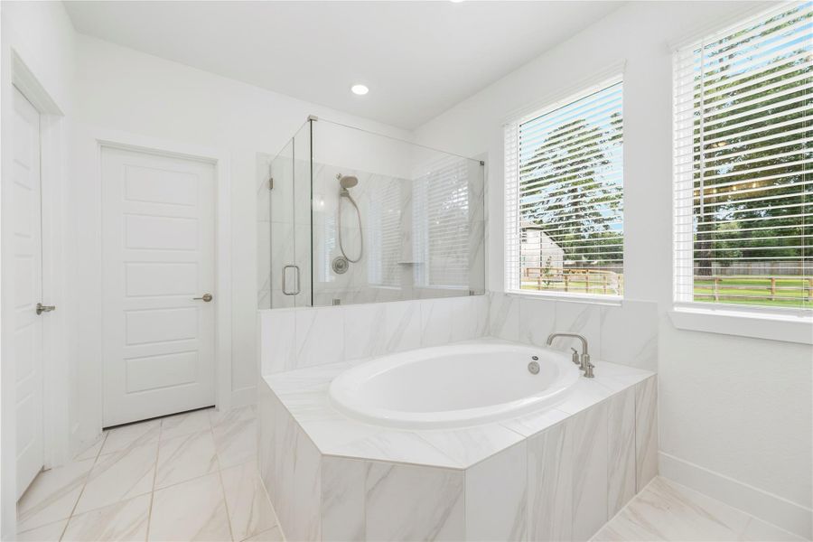 The spa-like primary bathroom is complete with dual vanities, soaking tub, frameless shower and a large walk-in closet.