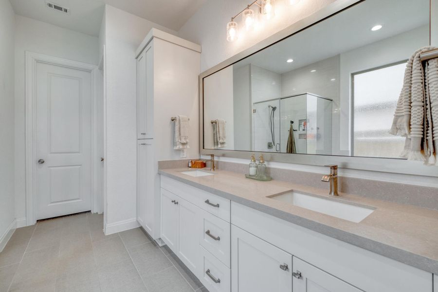 Floor-to-ceiling cabinetry gives the primary bath an impressive amount of tucked-away storage, while a  dual vanity gives everyone space.