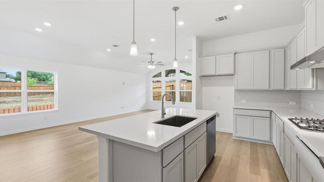 Contemporary kitchen featuring a center island with sink, white cabinetry, integrated gas range, and light wood-finish flooring Contemporary kitchen featuring a center island with sink, white cabinetry, integrated gas range, and light wood-finish flooring