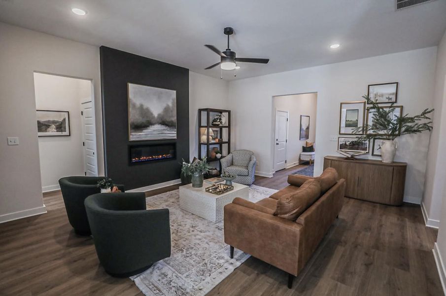 Living area featuring a modern fireplace with a dark accent wall, wood-finish flooring, recessed lighting, and a ceiling fan