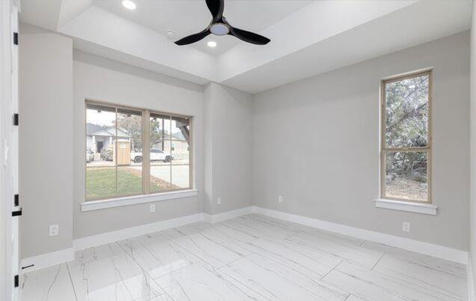 Spacious room featuring a tray ceiling with recessed lighting and a modern ceiling fan