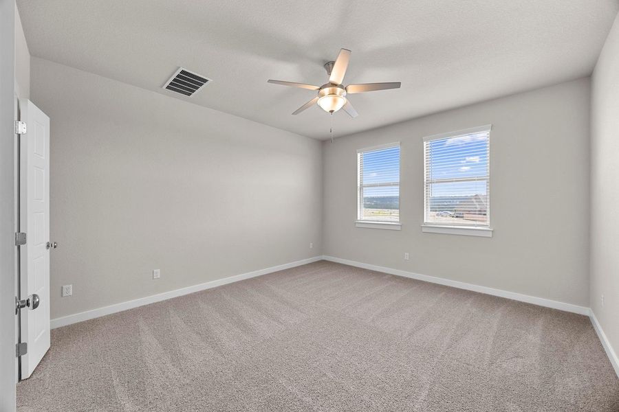 A well-lit bedroom features plush carpeting and a ceiling fan for comfort. A well-lit bedroom features plush carpeting and a ceiling fan for comfort.