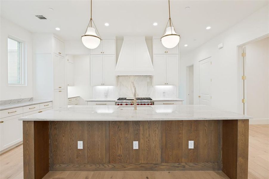 A statement island featuring natural wood cabinets serves as the centerpiece of the kitchen