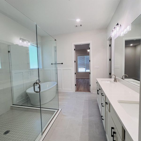 Freestanding soaking tub, glass-enclosed shower with tile surround, dual vanity with undermount sinks, and tile flooring Freestanding soaking tub, glass-enclosed shower with tile surround, dual vanity with undermount sinks, and tile flooring