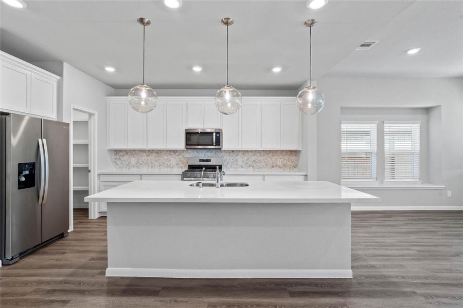 This modern kitchen island features a polished quartz countertop with an undermount double-bowl stainless steel sink, complemented by a Moen Integra chrome faucet with DuPure water filtration system.