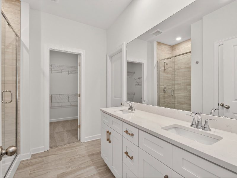 The primary bathroom boasts a dual-sink vanity and spacious walk-in shower.