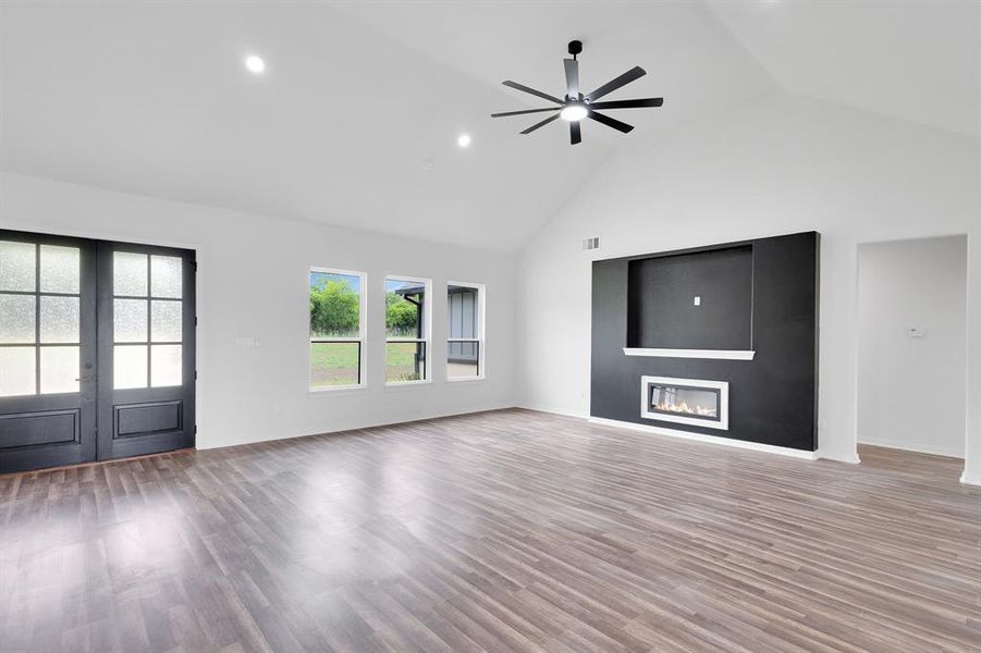 Expansive living area featuring vaulted ceilings, recessed lighting, and wood-look flooring