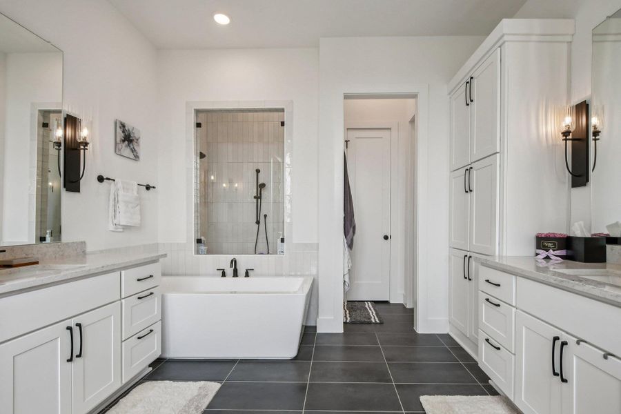 This bathroom features dual vanities with white cabinetry and light-colored countertops This bathroom features dual vanities with white cabinetry and light-colored countertops