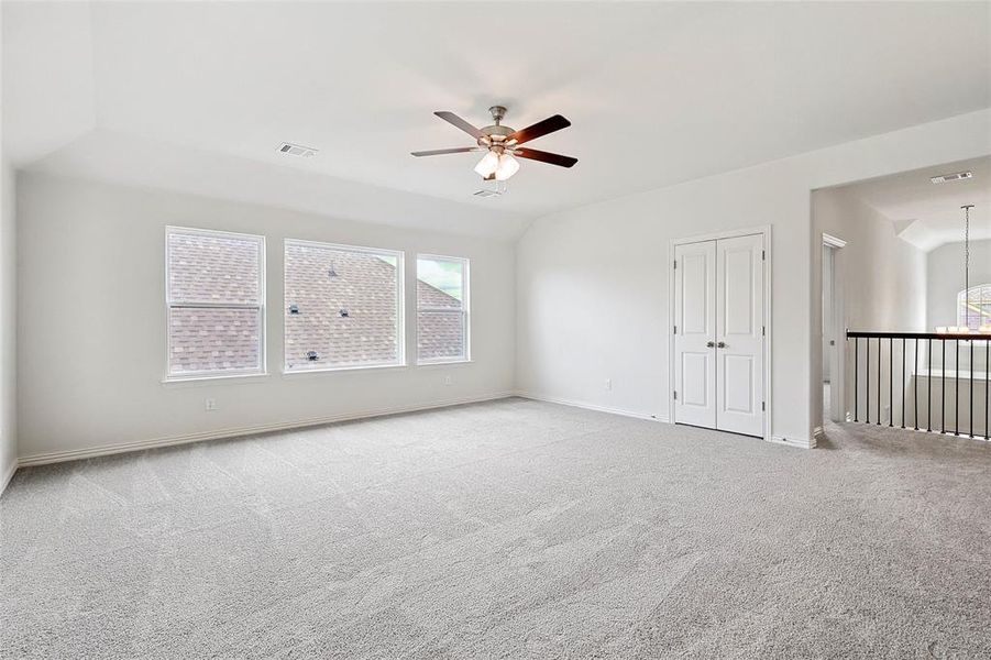 Spare room featuring light colored carpet, ceiling fan, and lofted ceiling