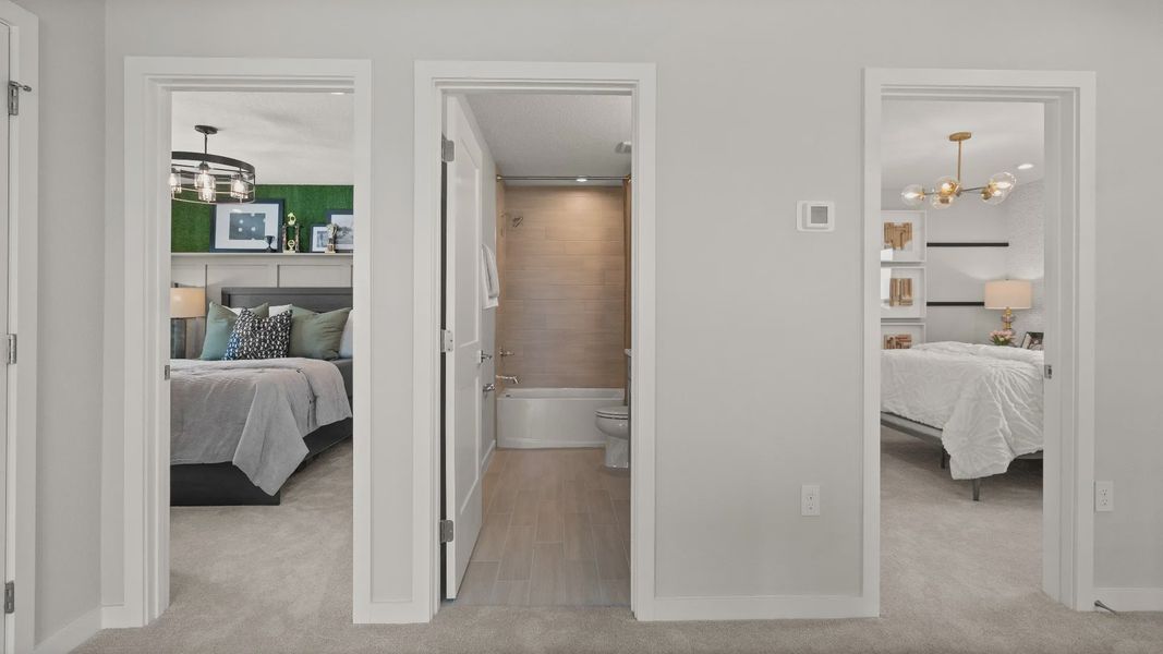 Hallway view of two bedrooms and a full bathroom in the Jupiter Model at Grasslands West by DRB Homes in Lakeland, Florida.