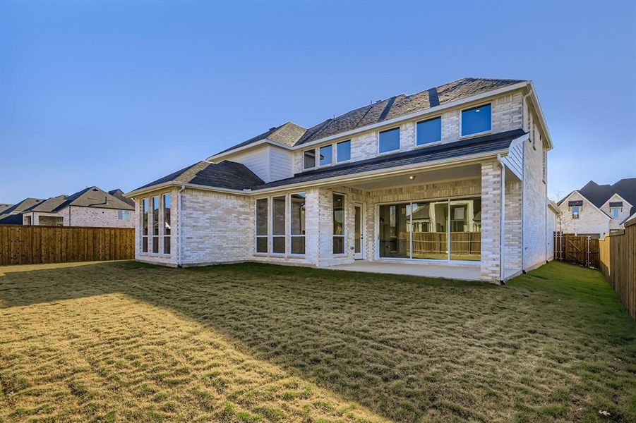 Rear view of property with a fenced backyard, a patio, and brick siding
