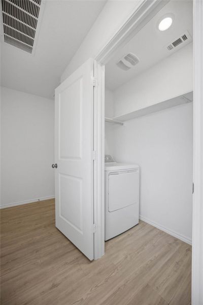 A dedicated laundry closet features vinyl flooring and built-in shelving above the utility hookups.