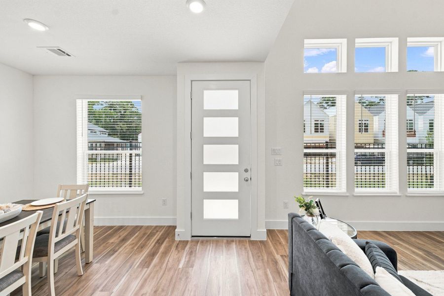Bright open-concept layout highlighting the modern front door, abundant windows, and easy flow between the living room and breakfast area. Bright open-concept layout highlighting the modern front door, abundant windows, and easy flow between the living room and breakfast area.