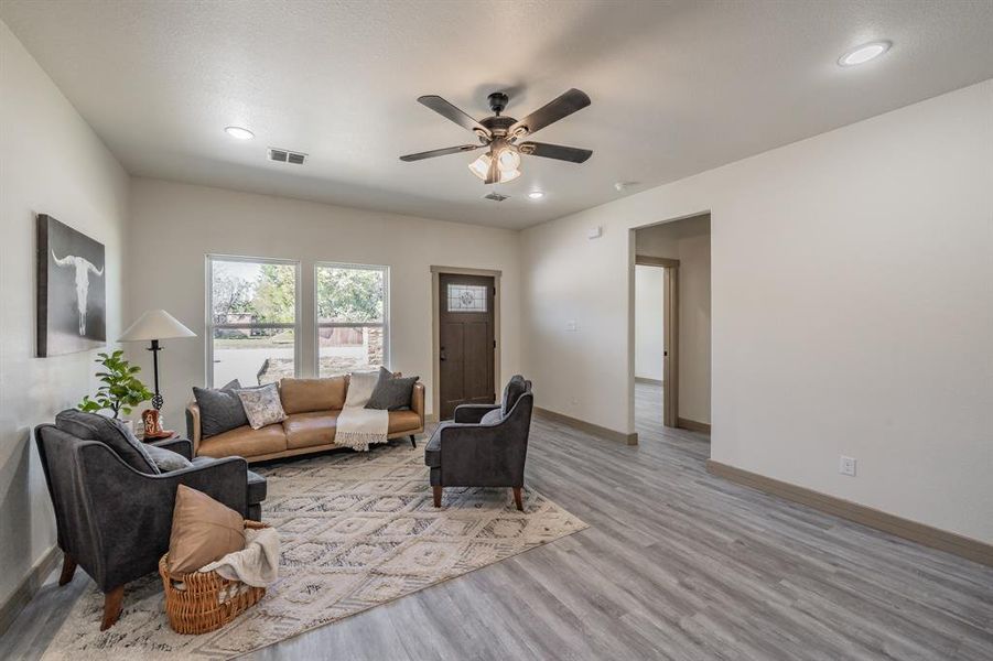 Living room featuring light wood-style flooring, ceiling fan, and recessed lighting
