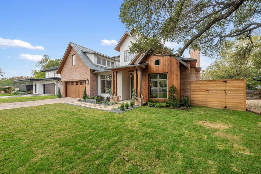 View of front of home with brick siding, a standing seam roof, a metal roof, driveway, and a chimney View of front of home with brick siding, a standing seam roof, a metal roof, driveway, and a chimney