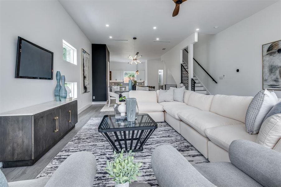 Living room with light hardwood / wood-style flooring and ceiling fan with notable chandelier