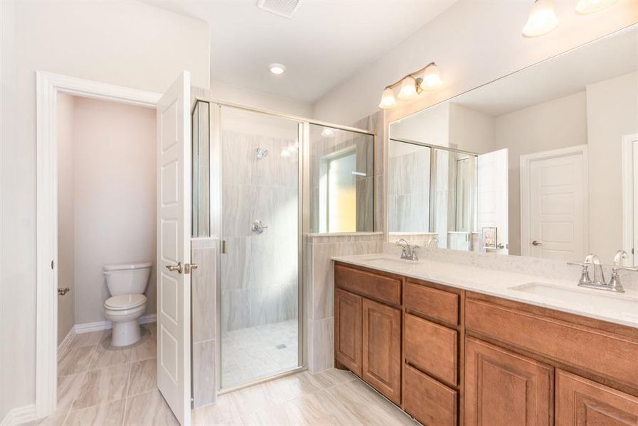 Full bathroom with double vanity, a sink, toilet, and a shower stall