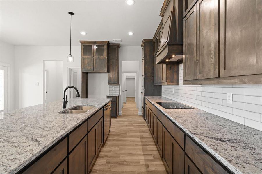 Kitchen with light stone counters, light wood-style flooring, dark brown cabinetry, pendant lighting, and recessed lighting Kitchen with light stone counters, light wood-style flooring, dark brown cabinetry, pendant lighting, and recessed lighting