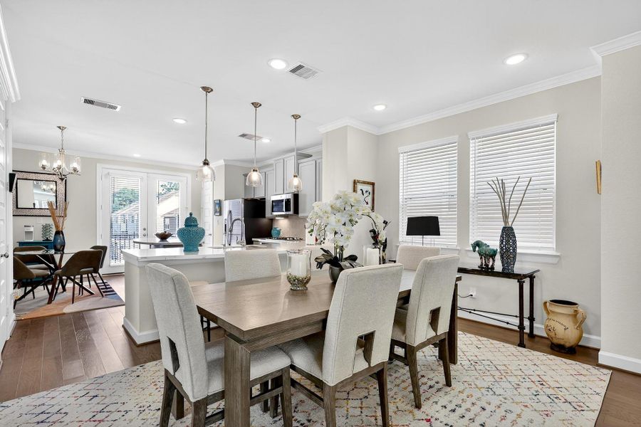 Spacious layout showcasing pendant lighting, a large island with breakfast bar seating, and access to the balcony through French doors. Spacious layout showcasing pendant lighting, a large island with breakfast bar seating, and access to the balcony through French doors.