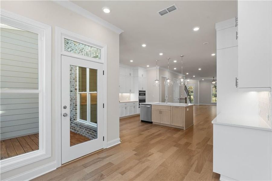 Kitchen featuring white cabinetry, light wood-type flooring, recessed lighting, pendant lighting, and open floor plan