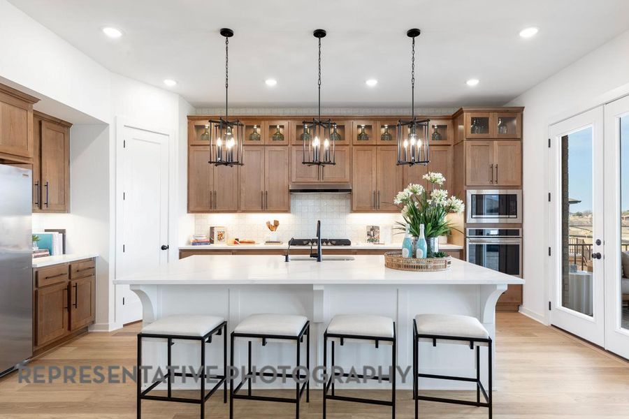 Kitchen with stainless steel appliances, brown cabinetry, tasteful backsplash, light countertops, and light wood-style flooring