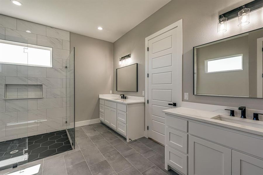 Bathroom featuring tiled shower, vanity, and tile patterned flooring