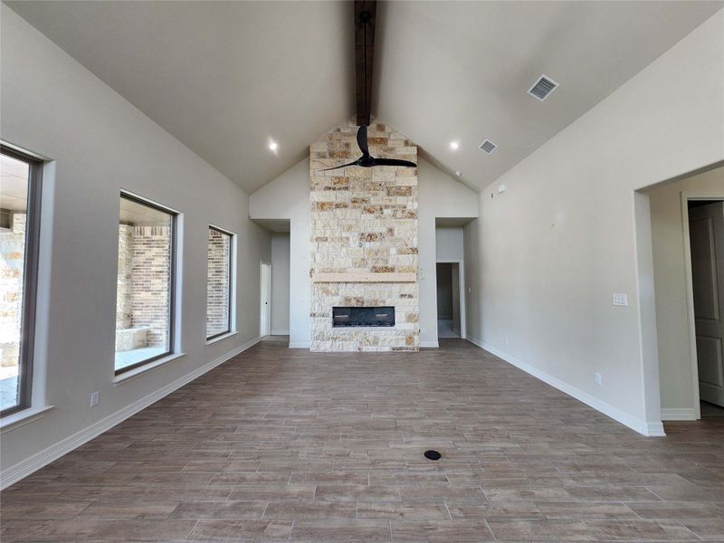 Unfurnished living room featuring dark wood-style floors and a stone fireplace