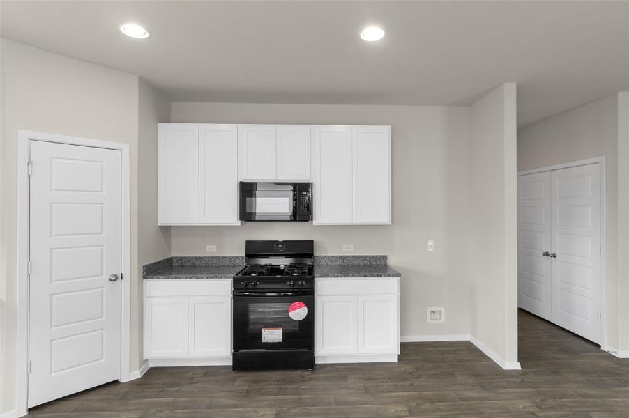 Kitchen with black appliances, dark wood finished floors, white cabinetry, and recessed lighting Kitchen with black appliances, dark wood finished floors, white cabinetry, and recessed lighting