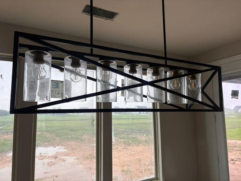 Rectangular chandelier featuring a black metal frame, six clear glass cylinder shades, and exposed filament bulbs