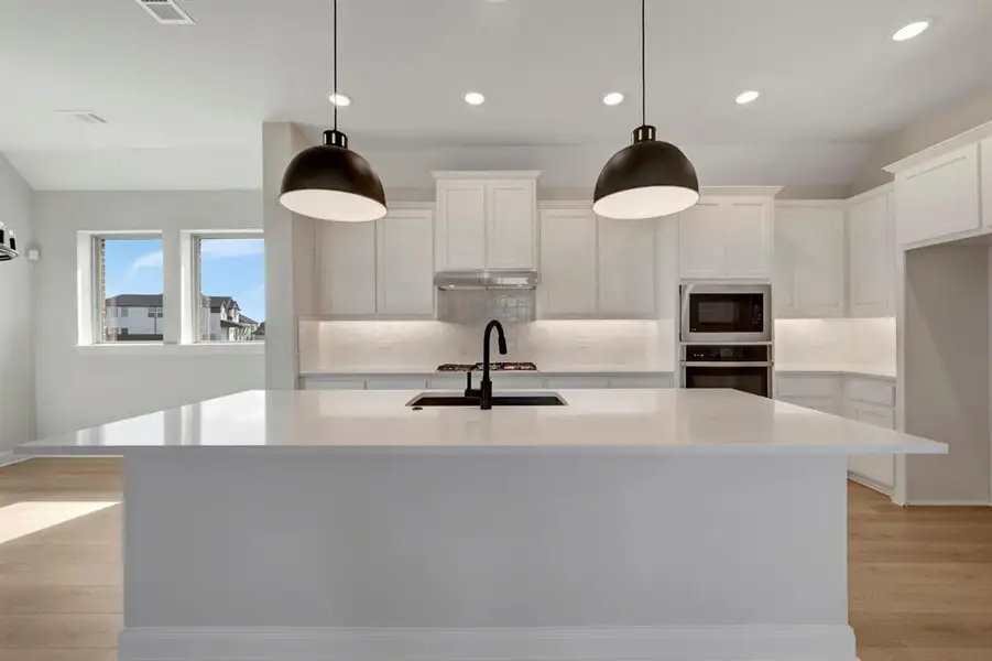 Kitchen with light wood-type flooring, white cabinets, a kitchen island with sink, and stainless steel appliances