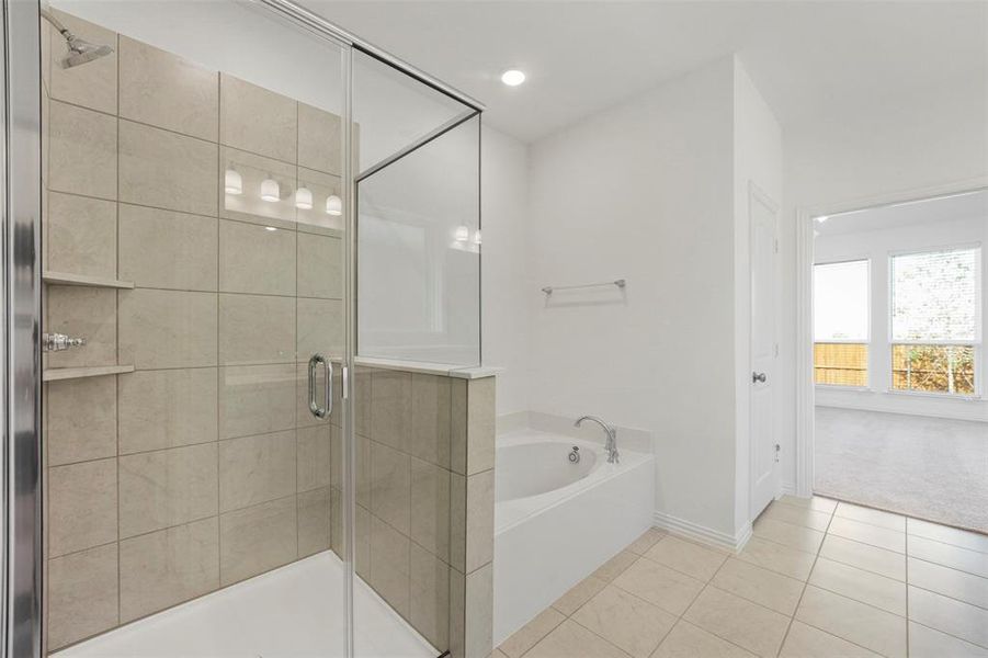 Bathroom with shower with separate bathtub and tile patterned floors